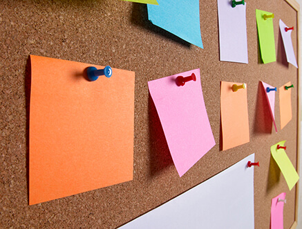 colorful square note cards pinned to a cork pin board to signify digital pinterest boards